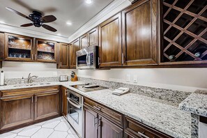 A kitchen with wooden cabinets, a microwave, and a granite countertop. - Resort Style, Heated Pool, Walk to Top Beach (Siesta Key)
