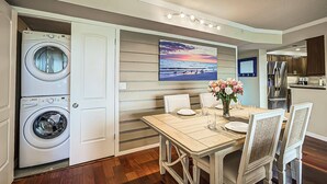 A compact kitchen with modern appliances, a dining area with a table set for two, and a large window with a view of the ocean. - Resort Style, Heated Pools plus Kiddie Pool, Walk to the Beach, On Bay, Tennis Courts (Siesta Key)