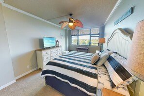 A bedroom with a bed, a desk, a television, and a window.
