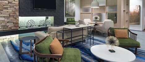 Uma sala de estar moderna com uma parede de destaque em pedra, uma TV de tela plana, um sofá verde, uma mesa de centro e uma área de jantar com mesa e cadeiras de madeira.