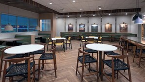 Ein modernes Restaurant mit runden Tischen und Stühlen, Sitzbänken und Kunstwerken an den Wänden.
