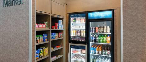 A corner market with shelves stocked with snacks and a refrigerated display with beverages.