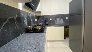 Una cocina con encimeras de mármol oscuro, un refrigerador de acero inoxidable y una estufa a gas.