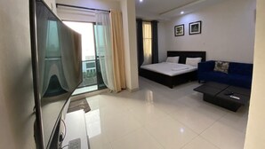 Una habitación de hotel moderna con cama, sofá, televisor y balcón con cortinas.