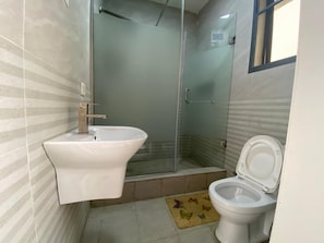 Un baño con lavamanos blanco, inodoro y cabina de ducha de vidrio.