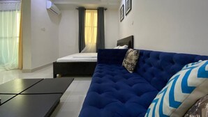 Una habitación de hotel moderna con una cama grande, un sofá azul y una mesita pequeña.