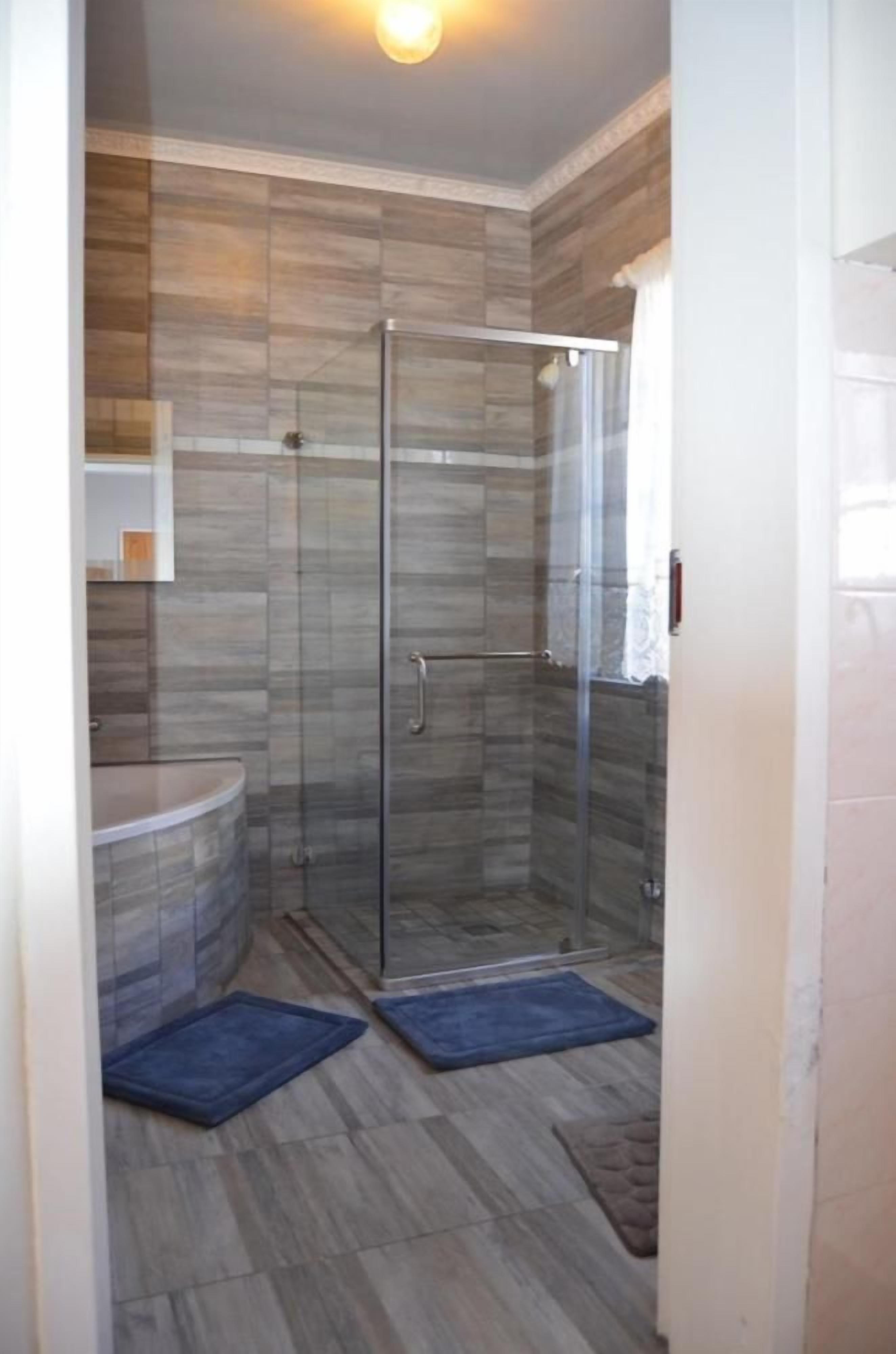 Un baño con ducha de vidrio, bañera y retrete.