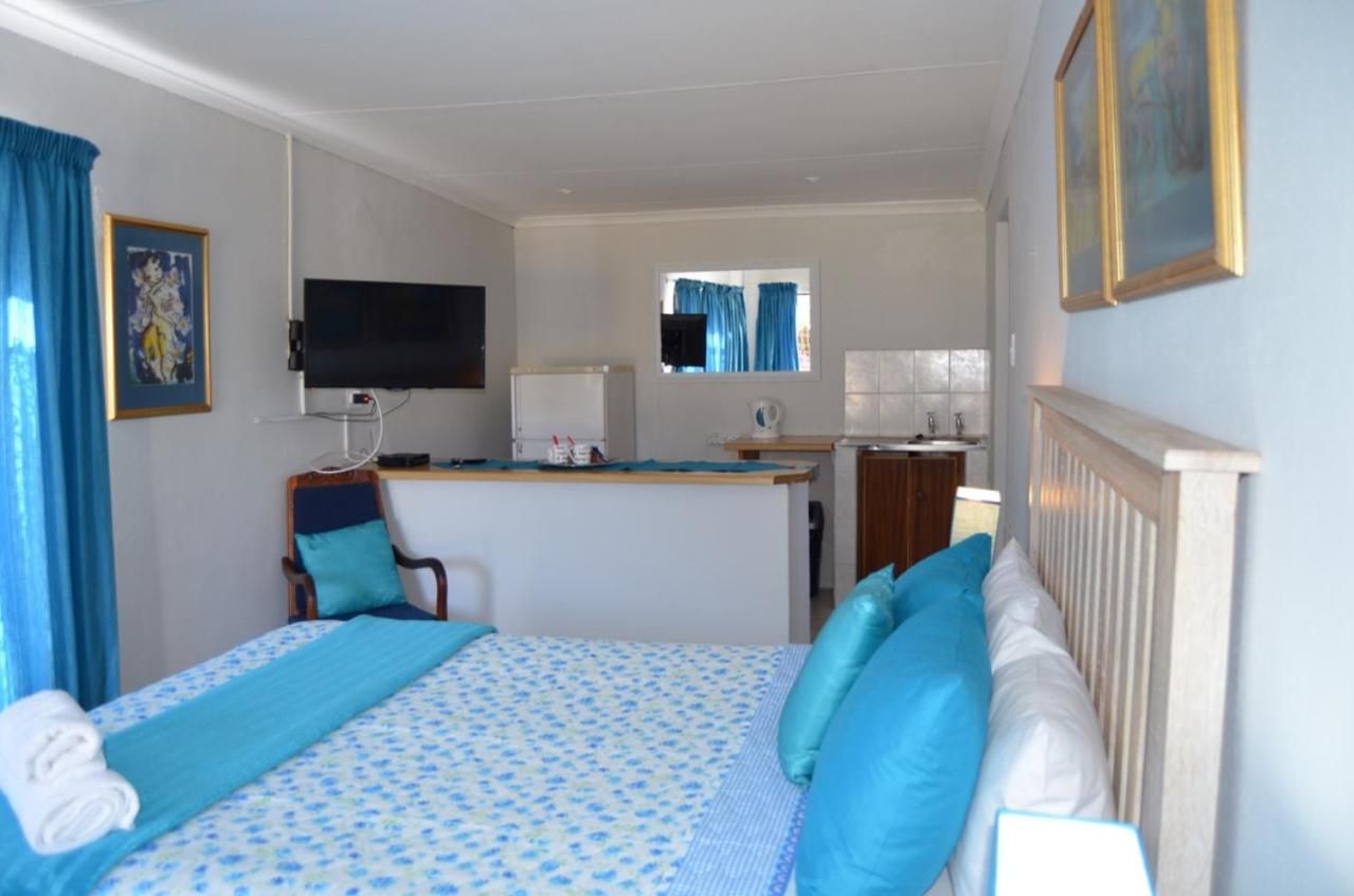 A hotel room with a bed, a desk with a computer, a television, and a window with curtains.
