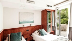 A hotel room with two beds, a wooden headboard, a large window with curtains, a painting on the wall, and a small table with a lamp. - 3 * apartments / 5pax. (Zaton)