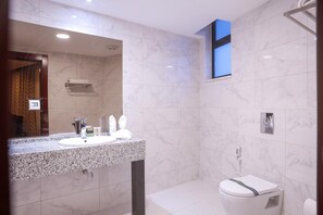 A modern bathroom with a granite countertop, a sink, and a toilet.