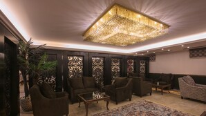 Un hall d’entrée spacieux, agrémenté d’un grand lustre, de plusieurs espaces de détente et de panneaux décoratifs.