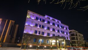 Un hôtel à plusieurs étages, doté d’une enseigne lumineuse et d’une entrée bien éclairée.