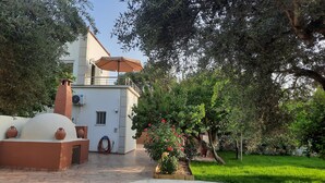 A two-story building with a balcony, a covered patio, and a garden with flowering plants. - Creta  Galini  House (Chania Creta)