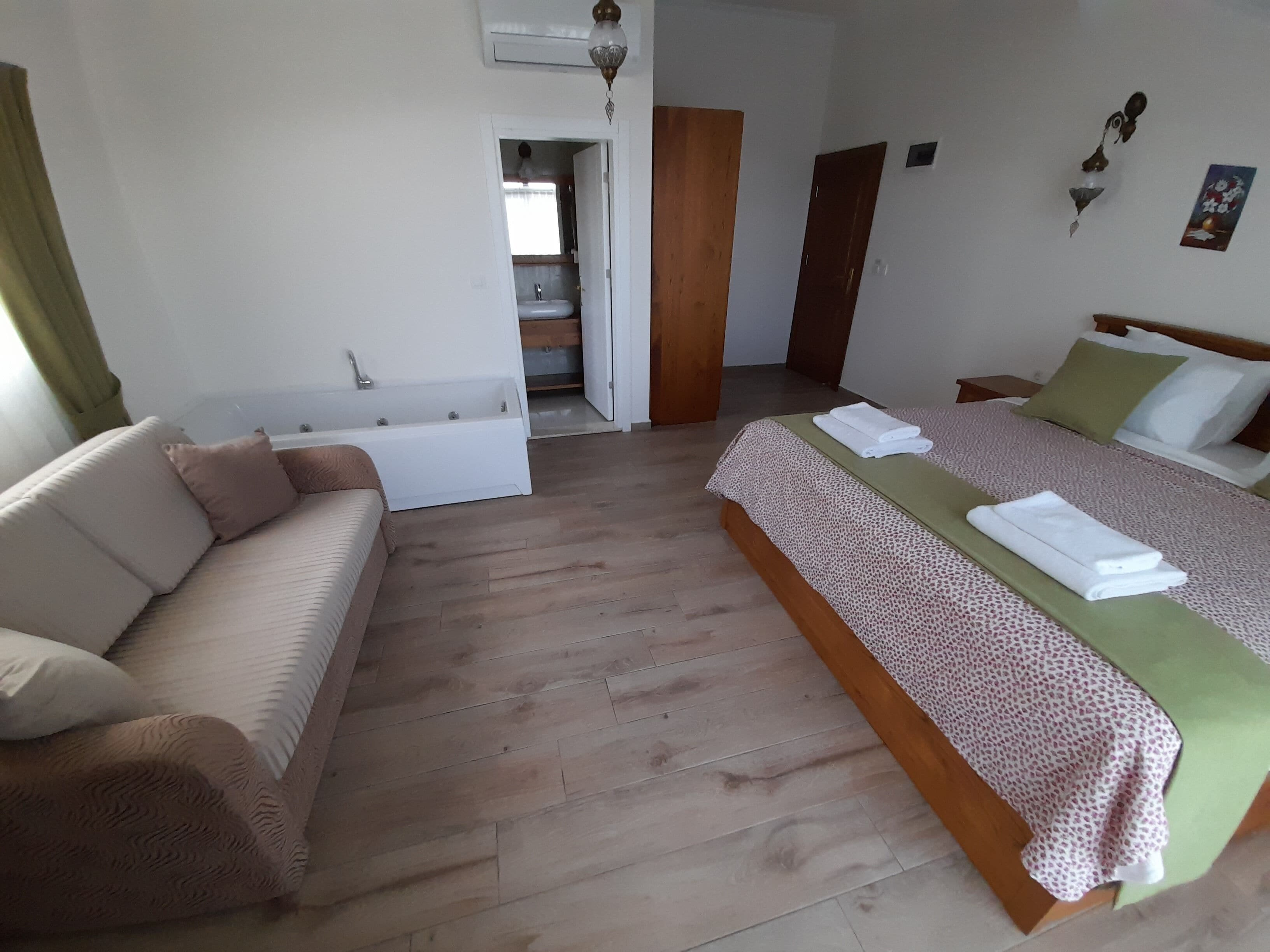 A bedroom with a bed, a sofa, and a bathroom visible through an open door.