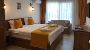 Habitación de hotel con una cama grande, un escritorio, un sofá y una ventana con cortinas.