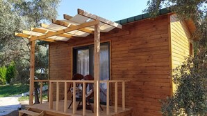 Una cabaña de madera con un porche, dos sillas y una mesita.