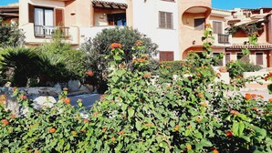 A Mediterranean-style building with a stucco exterior, terracotta roof tiles, and a balcony with a wooden railing. - Le Residenze La Marmorata (Santa Teresa di Gallura)