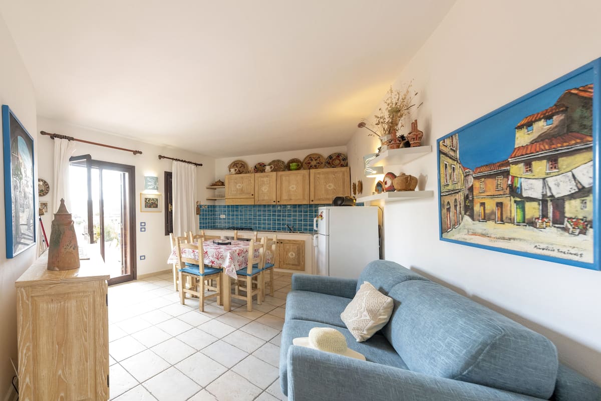 A cozy living room with a blue sofa and a dining area with wooden chairs and a table.
