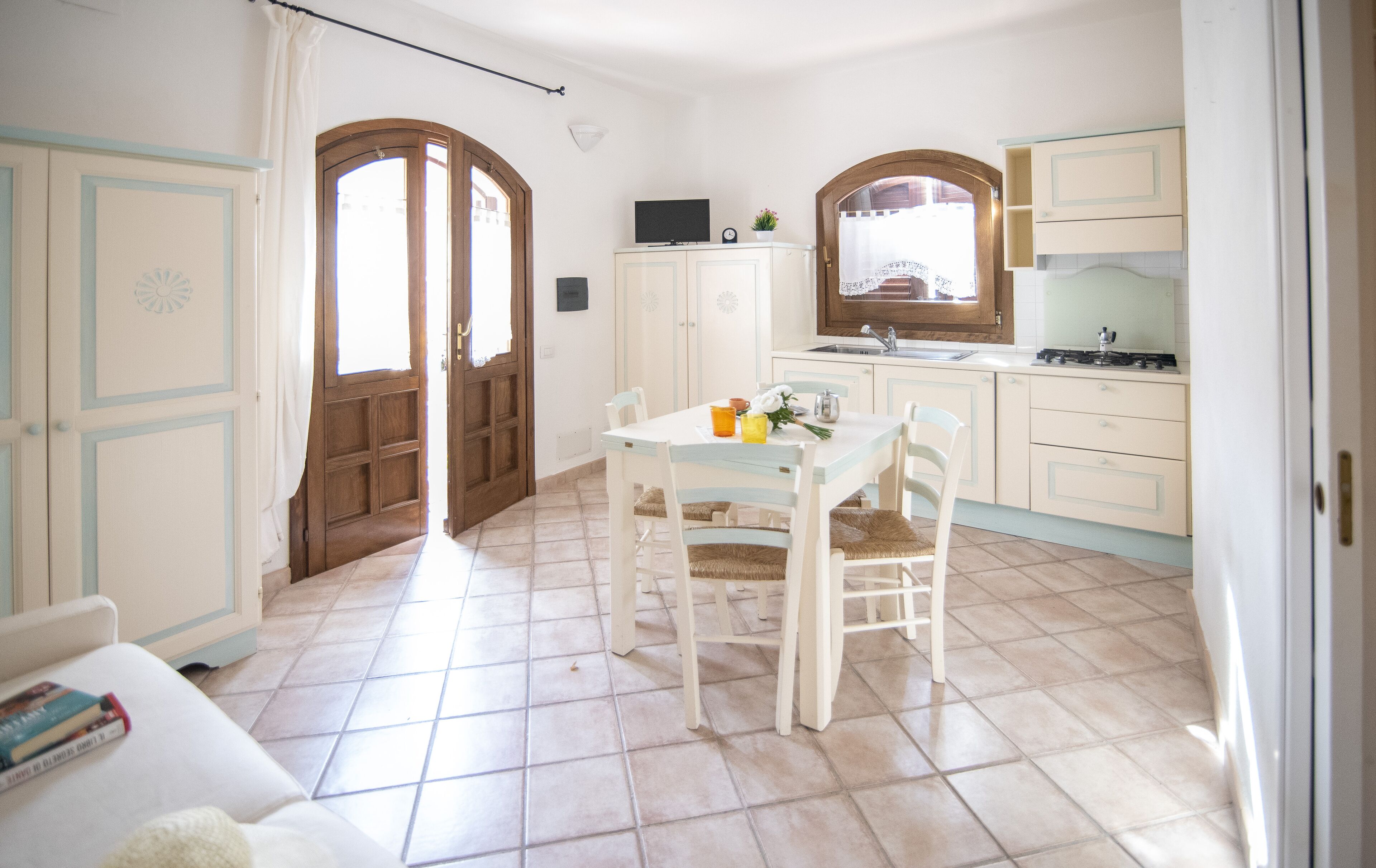 A kitchen with a dining table, chairs, cabinets, and a window.