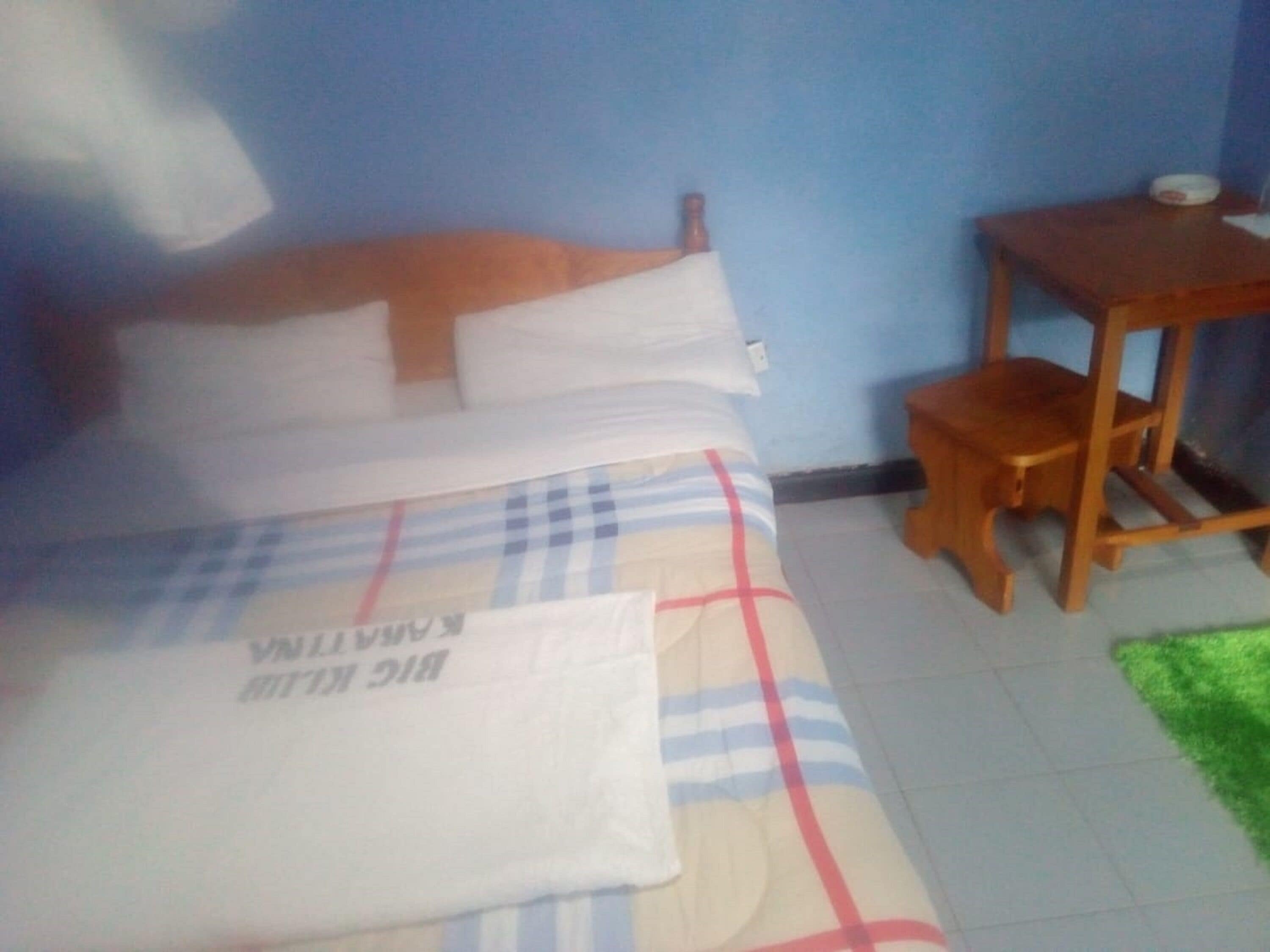 A bedroom with a bed, a wooden nightstand, and a small table.
