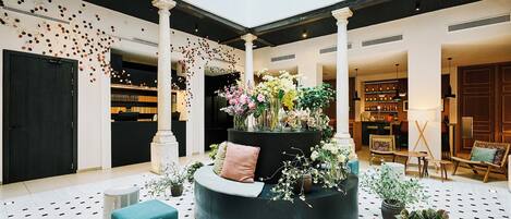A modern lobby with a central circular seating area, a reception desk, and a bar area.