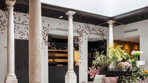 A spacious atrium with high ceilings, large windows, and a central seating area surrounded by columns. - TOC Hostel Málaga (Málaga)
