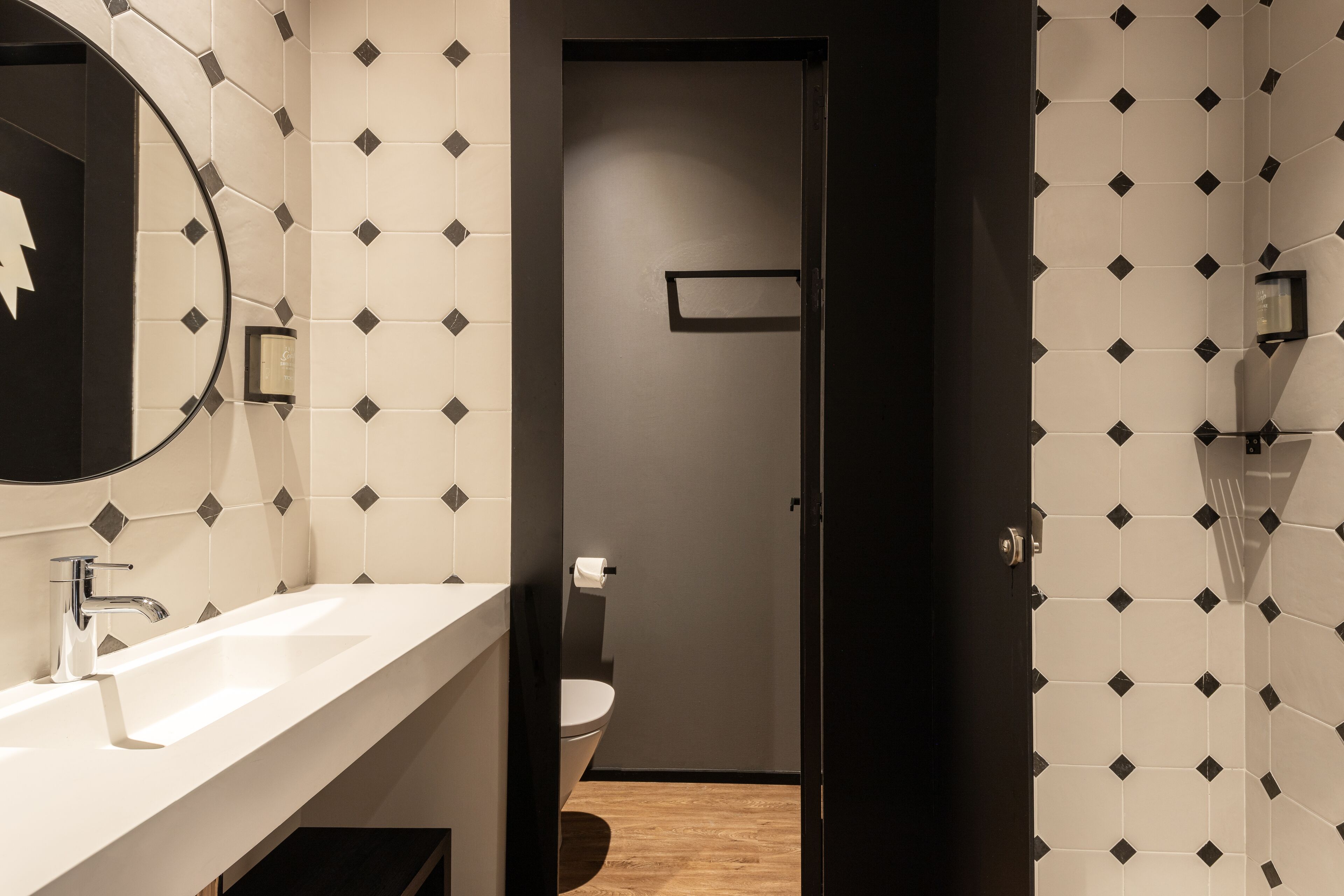 Un baño moderno con lavamanos blanco, un espejo y un inodoro.