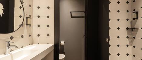 Un baño moderno con lavamanos blanco, un espejo y un inodoro.