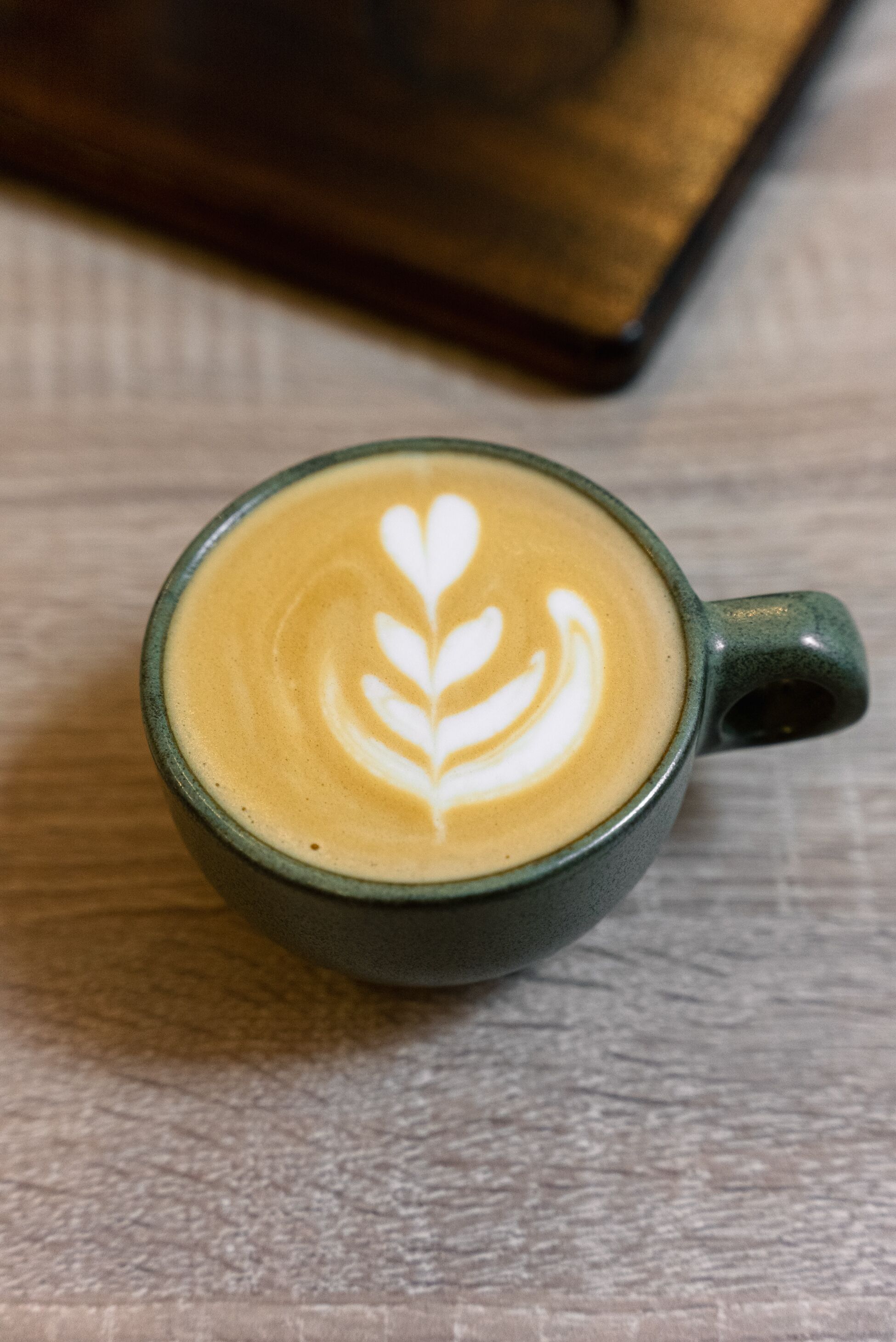 A cup of coffee with latte art on a wooden surface.