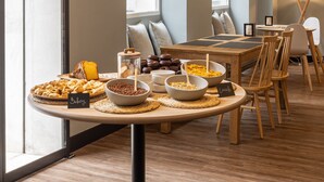 A breakfast buffet with various food items, a coffee station, and a seating area with tables and chairs. - TOC Hostel Málaga (Málaga)