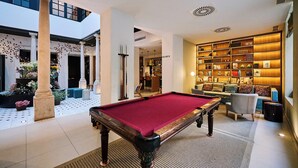 A billiards table in a well-lit indoor area with a bookshelf and seating. - TOC Hostel Málaga (Málaga)