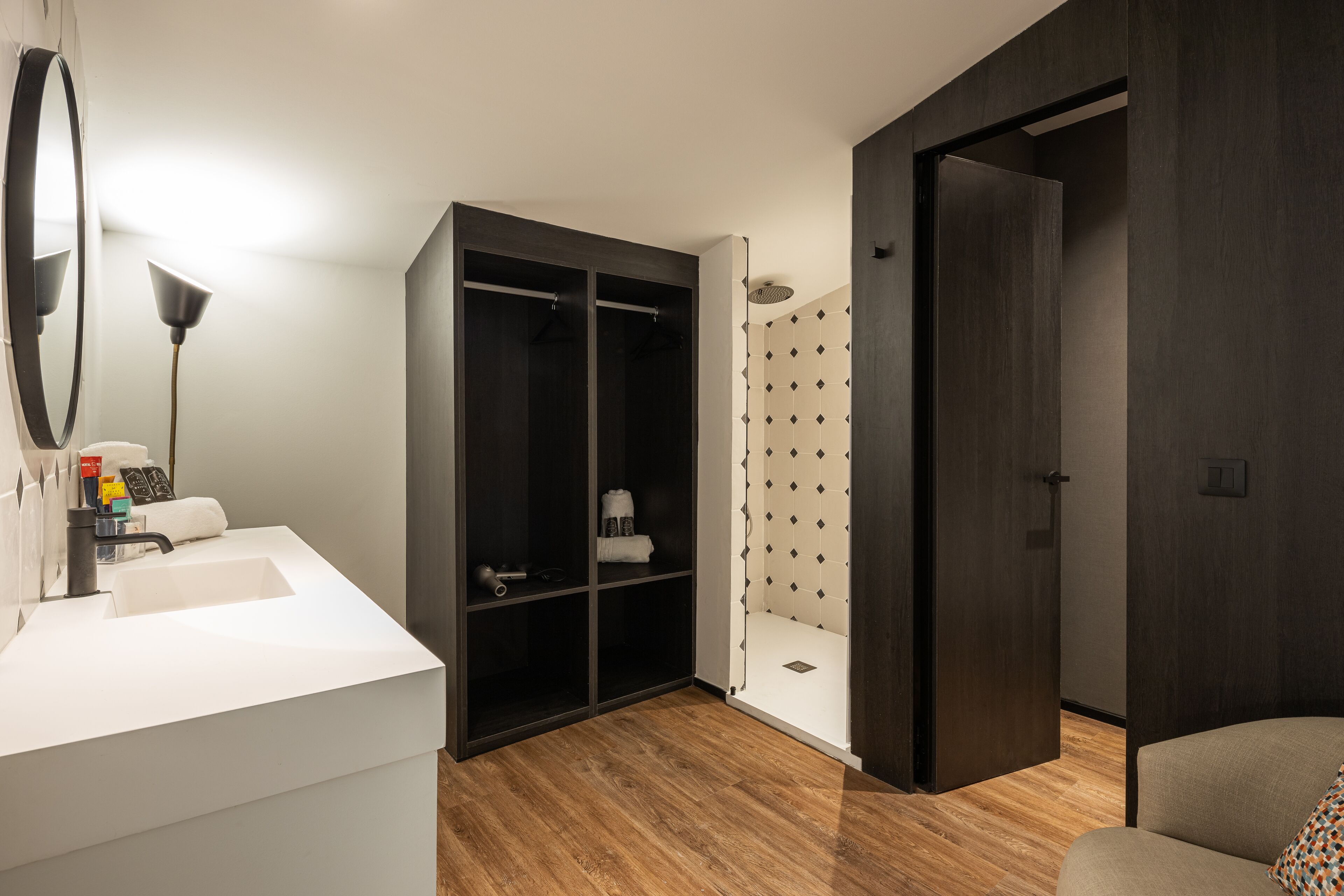 A modern bathroom with a white sink, dark wooden cabinets, a shower with patterned tiles, and a door leading to another room.