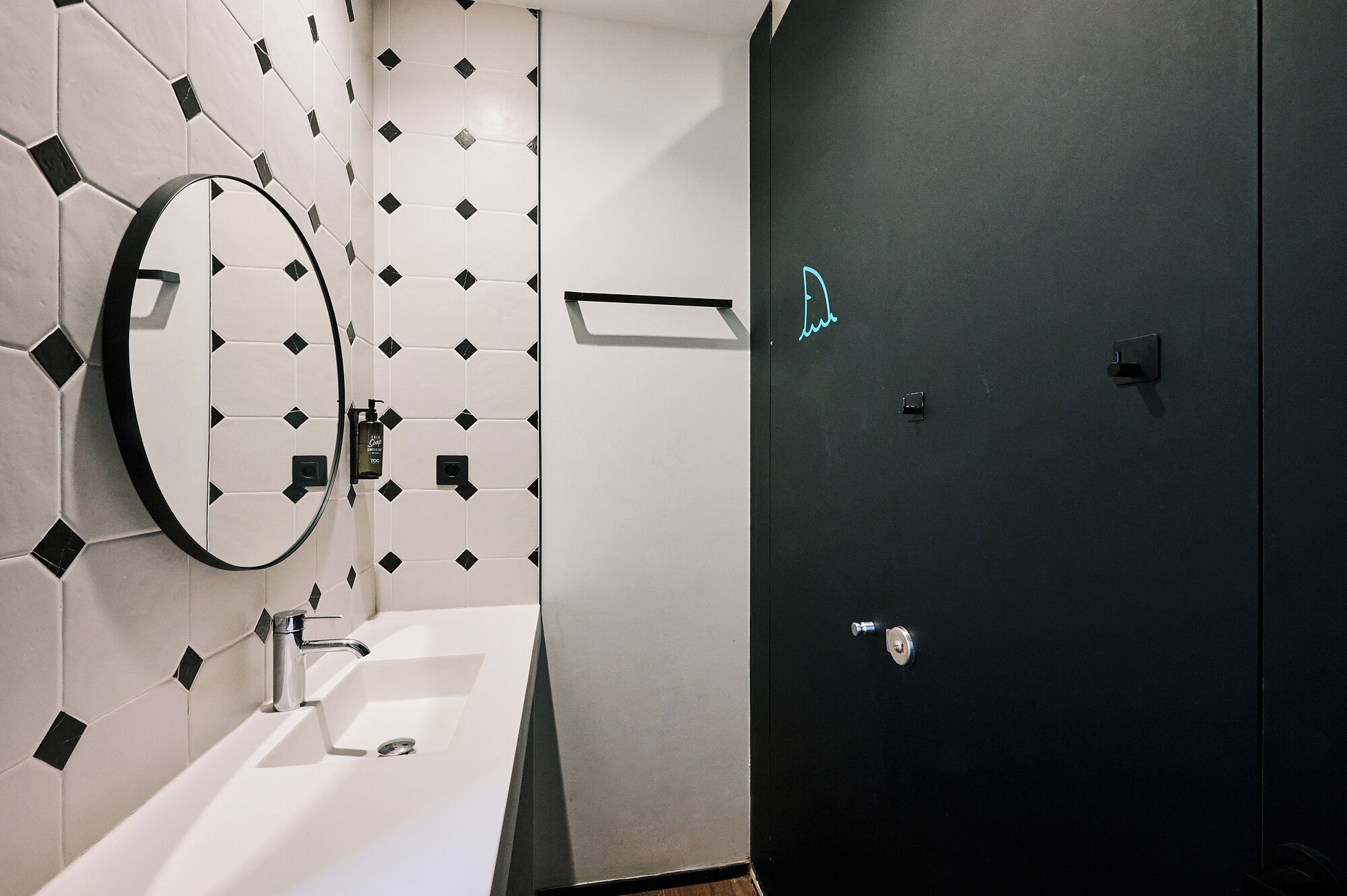 Une salle de bain moderne avec un lavabo blanc, un miroir et une porte noire.