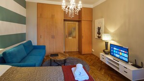 Ein Hotelzimmer mit einem Bett, einem blauen Sofa, einem Holzschrank, einer Kristallleuchter, einem Fernseher und einer Lampe.