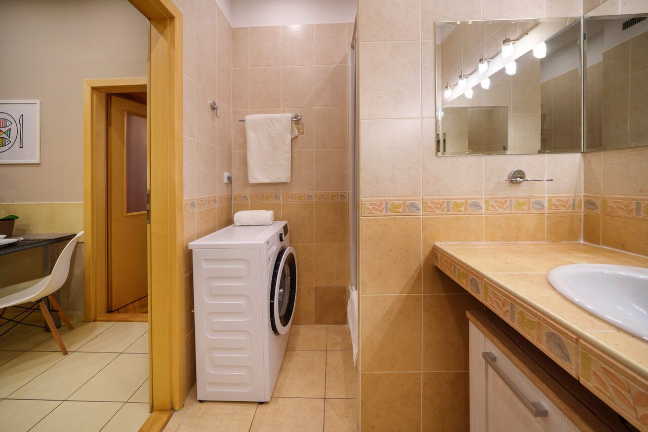 Un baño con lavadora, lavamanos y espejo.