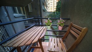 Ein Holztisch und ein Stuhl auf einem Balkon mit Blumentöpfen.