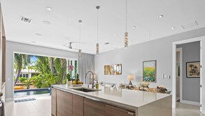 A modern kitchen with a large island, built-in appliances, and a view of a pool. - Heated Pool, Modern Spacious Waterway Home Offering Comfort, Style & Total Relaxation! (Wilton Manors)