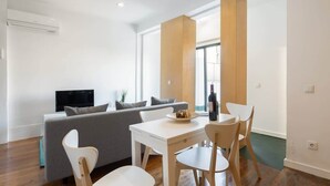 Una sala de estar moderna con un sofá gris, una mesa de comedor blanca y un televisor.