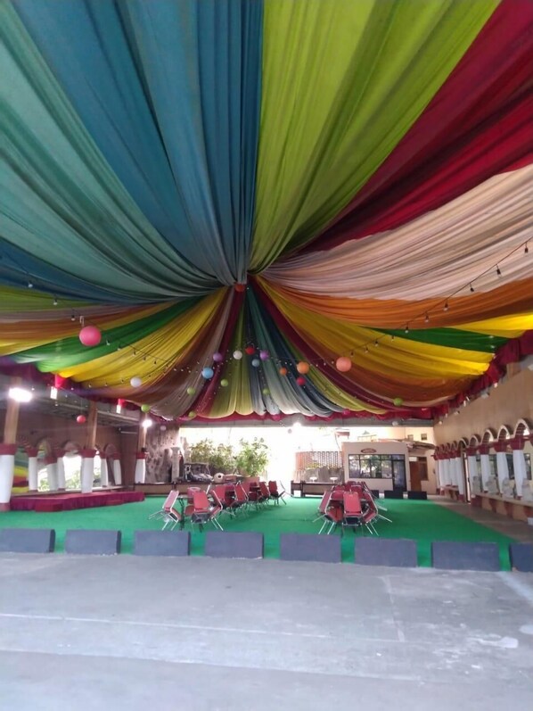 An indoor venue with a stage, chairs, and draped curtains. - Villa Tjokro (Cisarua)