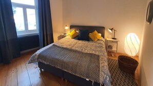 A bedroom with a bed, two bedside lamps, a window with curtains, a bedside table, and a floor lamp. - Central Graz Apartments by Paymán Club (Graz)