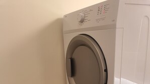 A front-loading washing machine with a wooden drying rack beside it. - Central Graz Apartments by Paymán Club (Graz)