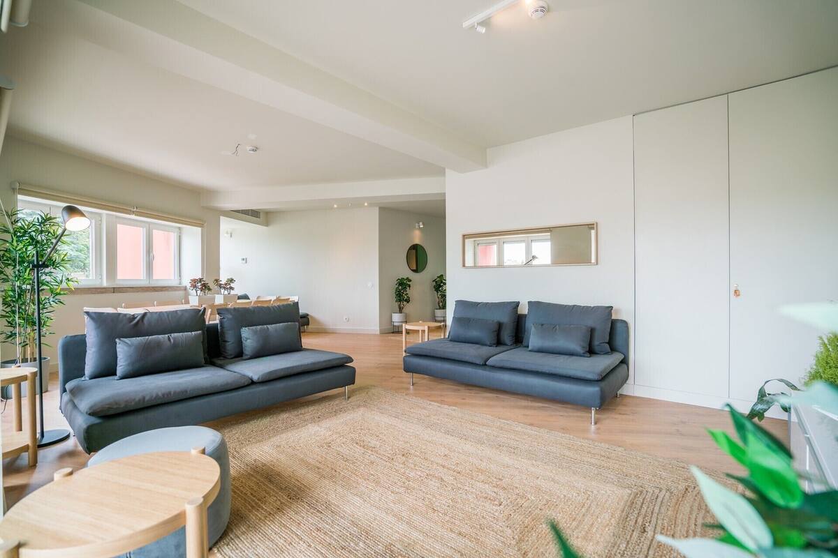 A modern living room with two grey sofas, a wooden coffee table, and a large woven rug.
