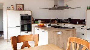 Une cuisine moderne avec des armoires blanches, un îlot central en bois et un four encastré.