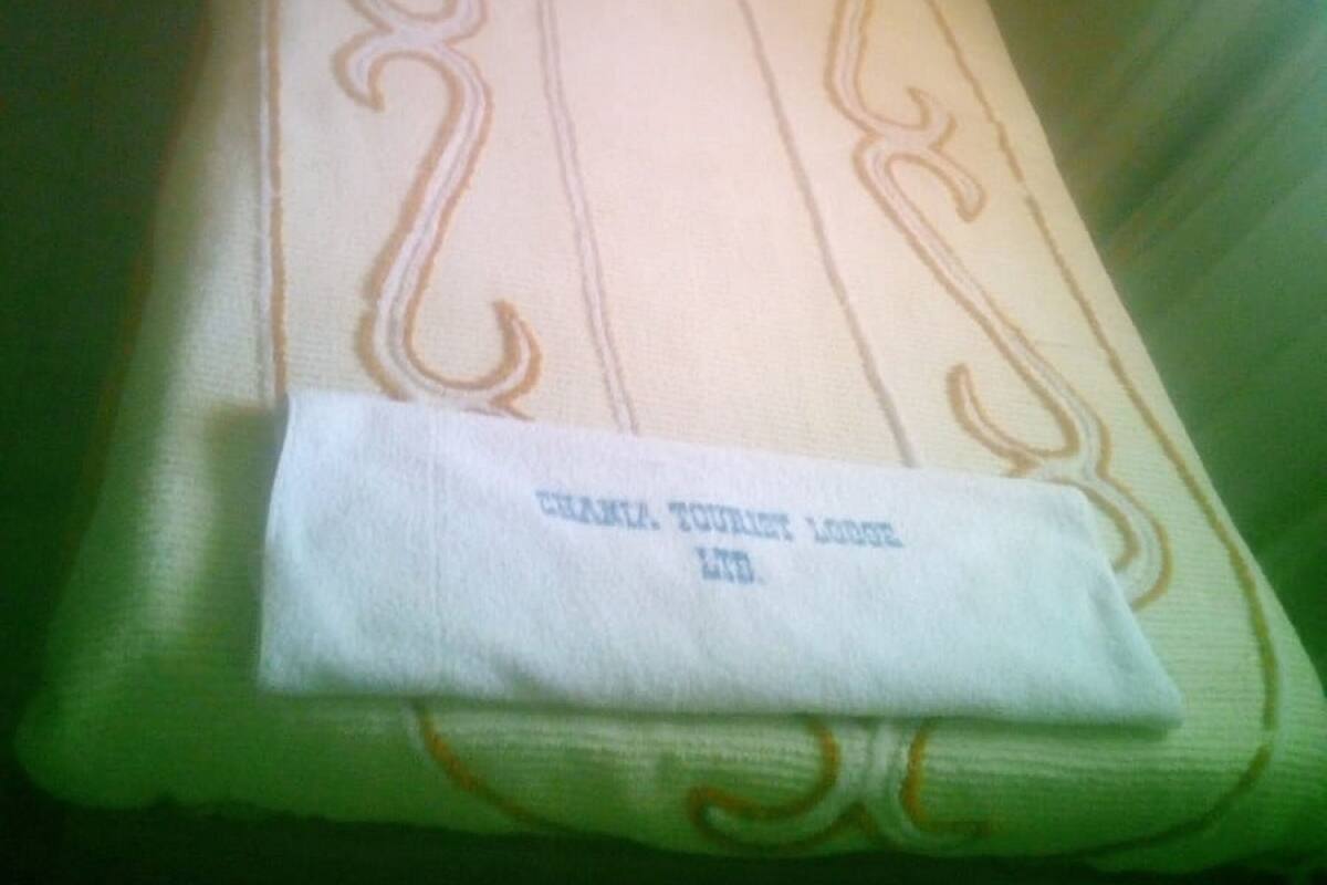 A neatly folded white towel with embroidered designs and a tag from "GRANZA TOURIST LTD."