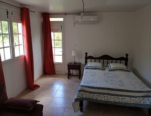 Une chambre à coucher avec un lit, une table de chevet, une lampe et une fenêtre avec des rideaux.