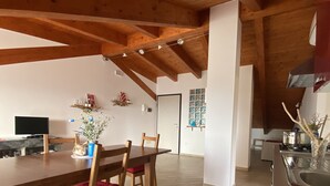 Un comedor amplio con una mesa y sillas de madera, una cocina al fondo y un piso con diseño de espiga.