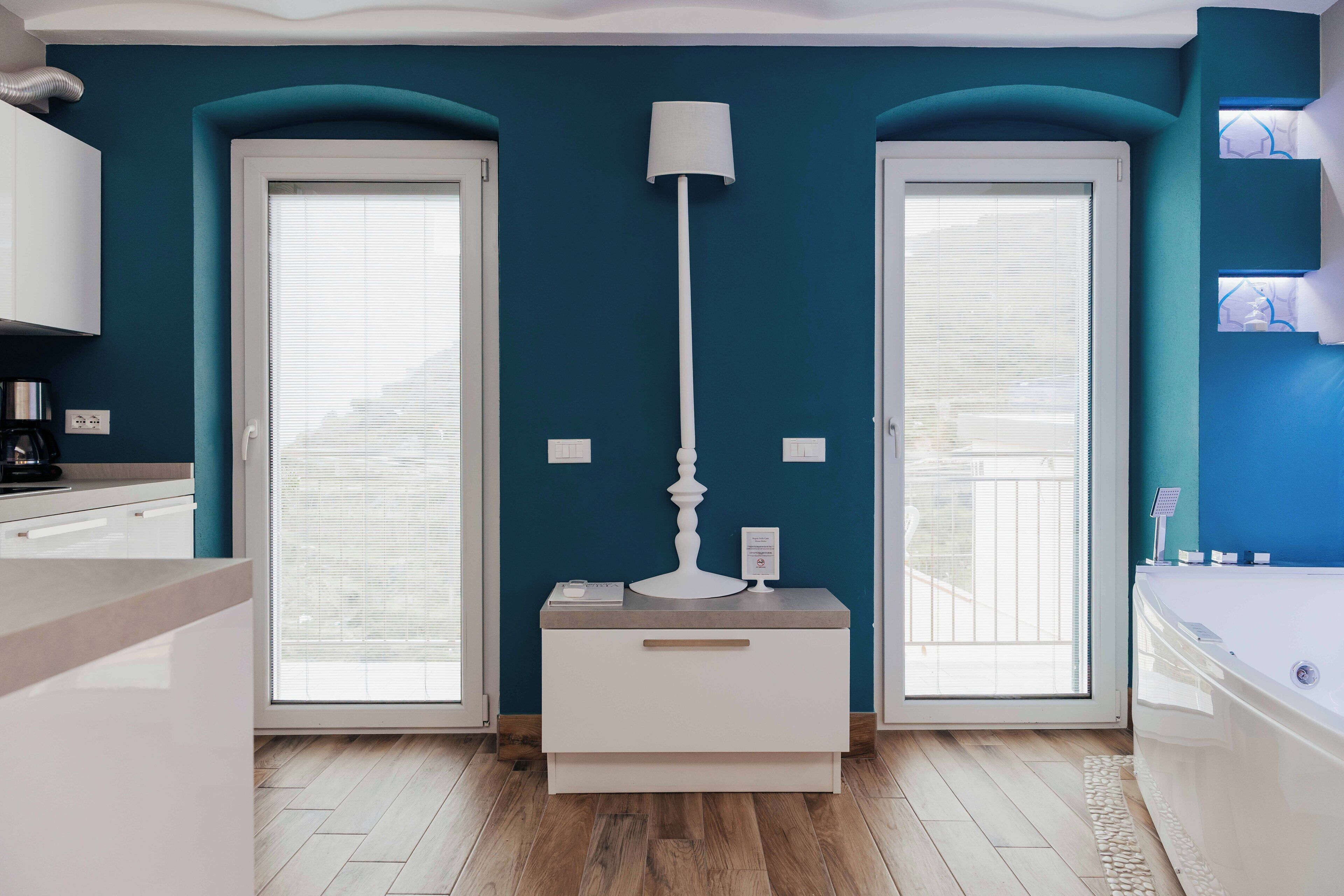 Ein modernes Badezimmer mit einer Badewanne, einem weißen Waschtisch mit Spiegel und einer Stehlampe.