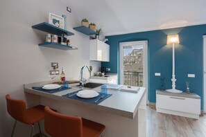 Une cuisine moderne dotée d’un îlot central, d’étagères bleues et offrant une vue sur l’extérieur.