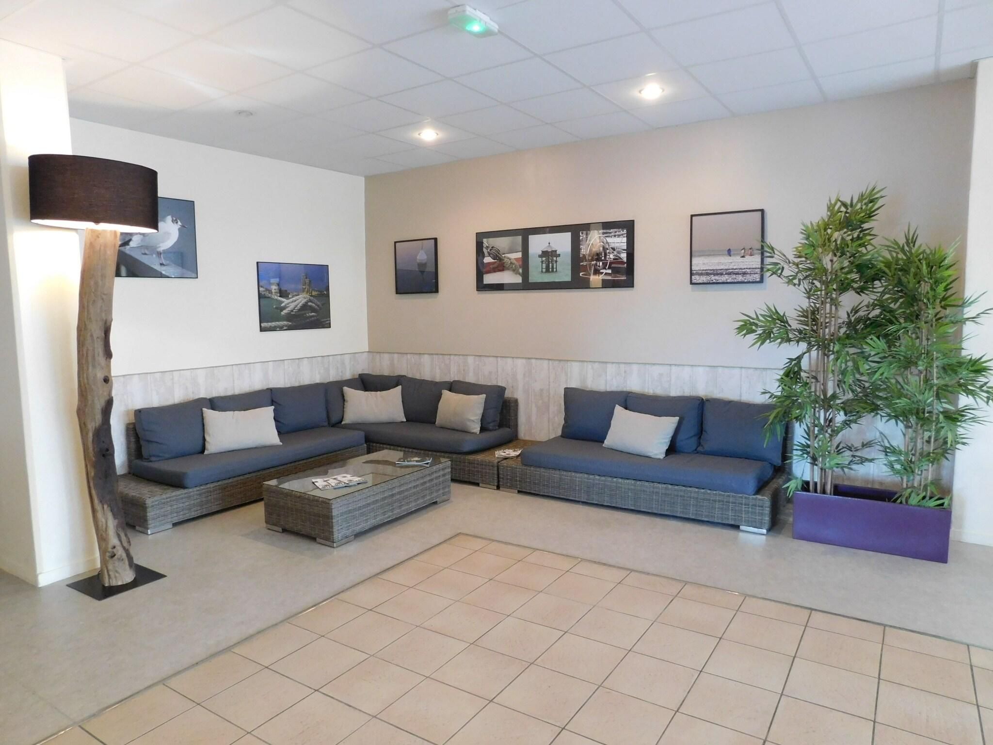 Un salon moderne avec un canapé d’angle, une table basse et une grande plante en pot.
