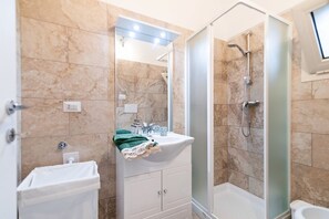 A bathroom with a shower, a sink, a mirror, and a towel.